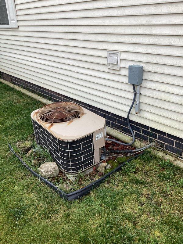 Conducted comprehensive evaluation of existing HVAC system for air conditioning replacement estimate. Customer requested AC-only replacement due to budget constraints. Documented current outdoor condenser unit showing significant age and weathering, with visible deterioration of housing and components. Unit positioned on plastic equipment pad against exterior wall with proper electrical disconnect and conduit installation. Interior inspection revealed aging ductwork with deteriorated tape and insulation, evidence of corrosion on pipe connections, and worn hose clamps requiring attention. Photographed all equipment conditions to support replacement recommendations. Provided estimate for new air conditioning system installation to address cooling needs within specified budget parameters.
