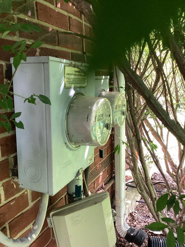 Completed comprehensive HVAC system replacement estimate for residential property. Assessed existing outdoor condensing unit location near electrical meter on exterior brick wall, noting vegetation clearance requirements for proper airflow and service access. Evaluated indoor air handler installation in utility area with existing ductwork and drainage systems, documenting current equipment configuration and spatial considerations for replacement unit sizing and positioning.