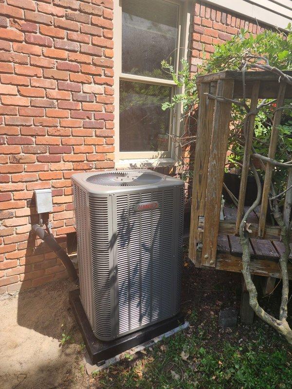 Completed installation of new Lennox air conditioning system at residential property. Replaced existing outdoor condenser unit with new Bryant model, positioning unit on composite pad against brick exterior wall beneath window. Connected refrigerant lines with brass fittings and completed electrical hookup with disconnect box mounted to wall via conduit. Replaced supply canvas ductwork and reinstalled UV light into new supply metal plenum. Installed new condensate pump with corrugated drain tubing routed to sump pump system for proper drainage. Verified all electrical connections, tested system operation, and confirmed proper airflow and cooling performance.
