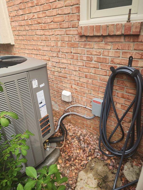 Completed installation of Lennox 4-ton variable speed condenser unit as warranty replacement. Unit positioned on concrete pad against exterior brick wall with proper clearances, connected to existing refrigerant lines and electrical disconnect. Removed and returned original condenser to shop per company protocol.