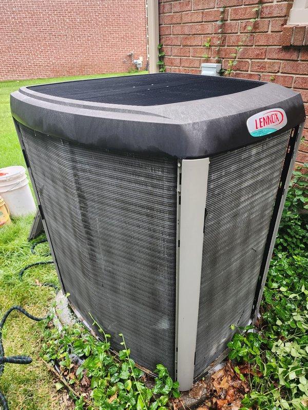 Completed scheduled AC maintenance on Lennox outdoor condenser unit. Performed comprehensive 10-12 point inspection including visual assessment of equipment condition, refrigerant lines, electrical connections, and condensate drainage system. Observed vegetation encroachment at unit base and organic debris accumulation in drip pan with visible rust staining and algae growth. Unit operational with normal outdoor weathering present on mesh grilles and components.