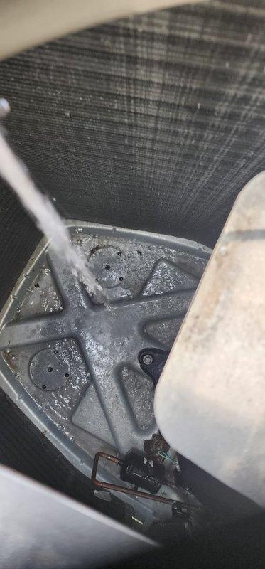 Completed scheduled cooling season maintenance on residential air conditioning system. Inspected indoor evaporator coil and drain pan, noting moisture accumulation and debris buildup in condensate collection area. Examined outdoor condensing unit, observing significant dirt and debris accumulation on condenser coil fins. Documented system condition with photographs showing internal components requiring attention during maintenance visit.