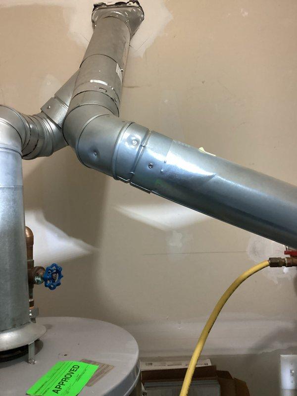 Completed estimate for 10-12 SEER air conditioning system replacement in utility room. Assessed existing ductwork configuration including galvanized metal T-junction connections and evaluated installation space adjacent to water heater with gas line. Documented current HVAC unit with filter access and rigid metal ductwork connections for replacement specifications.