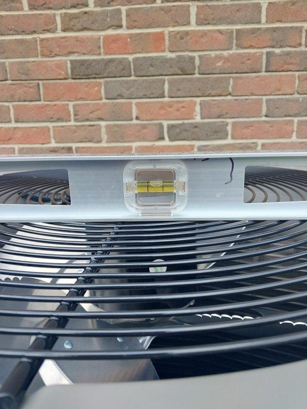Responded to warranty call for air conditioning unit releveling. Upon arrival, inspected outdoor condenser unit positioned against brick exterior wall and found unit had settled out of level. Utilized precision bubble level to verify equipment positioning and adjusted unit to manufacturer specifications using pea gravel base material. Confirmed proper leveling to ensure optimal compressor operation, drainage function, and equipment longevity. Unit tested and verified level in all directions upon completion.
