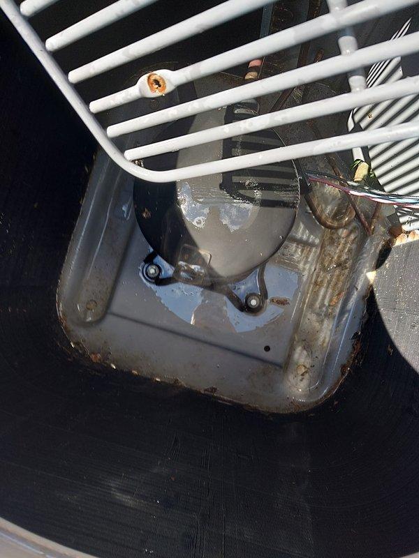 Completed scheduled cooling system maintenance on residential air conditioning unit. Performed comprehensive inspection of outdoor condenser unit, which showed normal operational wear with minor vegetation growth around concrete pad perimeter. Inspected condensate drain pan assembly, noting significant rust and corrosion buildup along edges and seams indicating extended service exposure to moisture. System operational and maintaining proper cooling function at time of service completion.