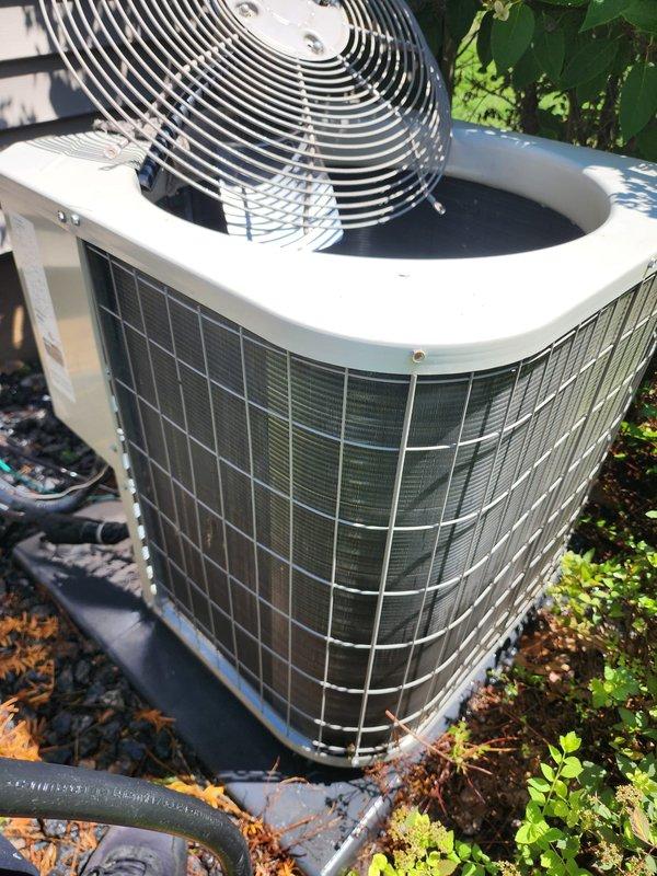 # HVAC Maintenance Visit with Refrigerant System Issue

Performed scheduled air conditioning tune-up on residential outdoor condensing unit under prepaid maintenance plan. Upon inspection, discovered severe frost and ice accumulation on compressor assembly inside air handler, indicating refrigerant system malfunction. Frost buildup extended across compressor top surface, sides, and surrounding components, suggesting potential low refrigerant charge, restricted airflow, or metering device failure.

Documented conditions with photographs showing heavily frosted compressor with ice crystallization on black cylindrical housing, copper refrigerant lines, and mounting base. Exterior condenser unit inspection revealed standard operational appearance with protective wire grille housing and top-mounted fan assembly in functional condition. Unit positioned on ground-level pad with refrigerant lines running to structure.

The extensive frost formation indicates system is not operating within norm