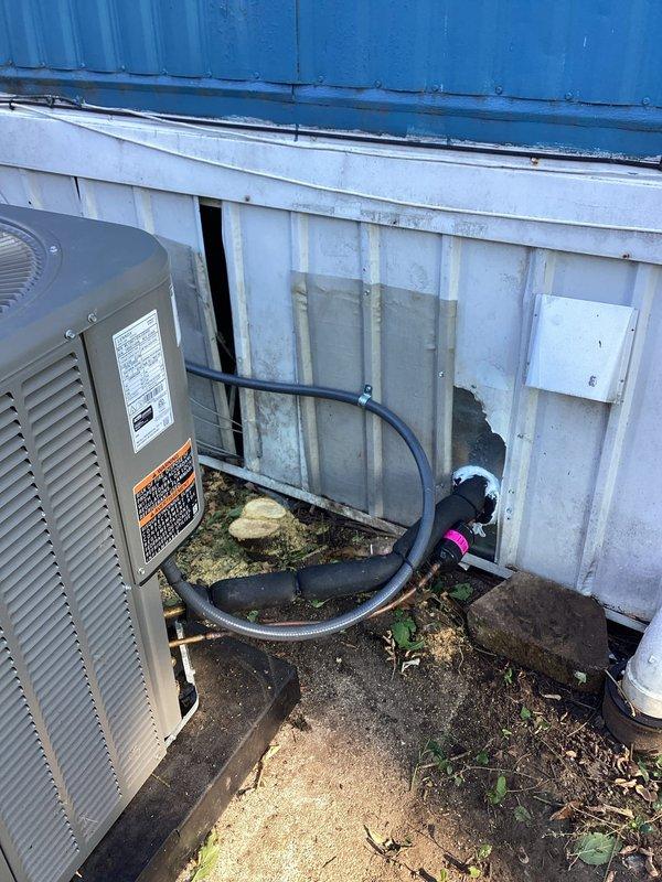 Completed warranty service on Bryant condenser unit addressing mechanical and refrigeration concerns. Removed excessive plant material and vegetation that had grown into and around the condenser unit, clearing all obstructions from louvers and airflow paths to restore proper operation. Sealed penetration point where refrigerant lineset enters building foundation to prevent air infiltration and pest entry. Installed proper-sized collar on chimney penetration to seal open areas around flue pipe per code requirements. Documented all conditions and repairs with photographs for warranty records.