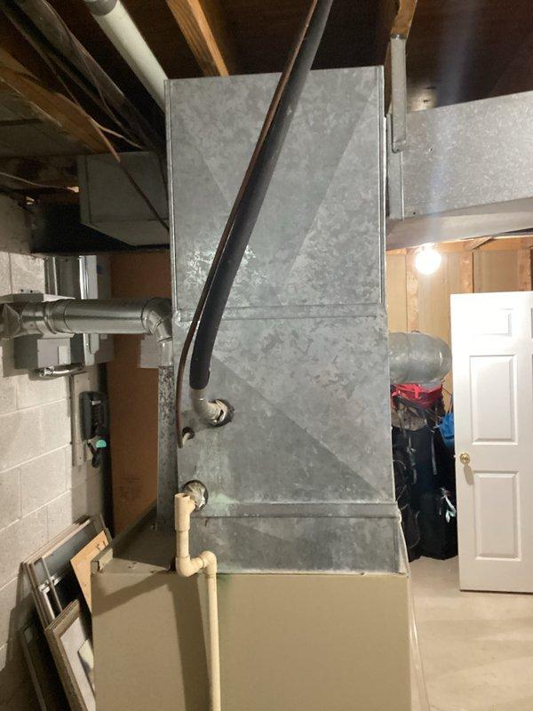 Conducted comprehensive estimate for full HVAC system replacement on 1,900 square foot ranch home with 40-year-old furnace and air conditioning equipment currently in operation. Assessed existing two-tone galvanized and beige furnace unit located in basement utility area with metal ductwork connections to ceiling joists, along with associated air conditioning system. Evaluated installation requirements including existing PVC drainage, ductwork configuration, electrical connections, and clearance specifications for modern high-efficiency replacement equipment suitable for single-story residential application.
