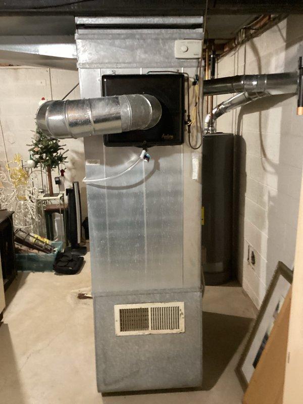 Conducted comprehensive estimate for full HVAC system replacement on 1,900 square foot ranch home with 40-year-old furnace and air conditioning equipment currently in operation. Assessed existing two-tone galvanized and beige furnace unit located in basement utility area with metal ductwork connections to ceiling joists, along with associated air conditioning system. Evaluated installation requirements including existing PVC drainage, ductwork configuration, electrical connections, and clearance specifications for modern high-efficiency replacement equipment suitable for single-story residential application.