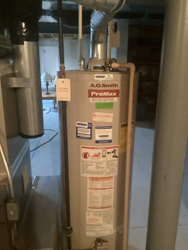 Conducted on-site assessment of existing A.O. Smith ProMax water heater located in basement utility area for replacement estimate. Documented current unit configuration including copper supply line connections, top-mounted valves and fittings, expansion tank setup, and surrounding HVAC equipment proximity. Photographed existing installation to provide accurate replacement specifications and identify any necessary modifications to plumbing connections or venting requirements for new water heater installation.