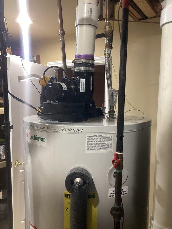 Conducted on-site evaluation for tankless water heater conversion at residential property. Customer currently operates a Lochinvar brand tank-style water heater with integrated recirculation pump system. Assessed existing installation including all supply and return plumbing connections, venting configuration, gas line sizing, and electrical requirements. Documented current equipment specifications and utility room layout. Photographed existing tank water heater installation showing recirculation pump assembly, copper supply lines with shutoff valves, PVC venting system, and associated plumbing infrastructure. Evaluated overhead mechanical space including existing gas lines, water distribution piping, HVAC ductwork proximity, and available clearances for tankless unit installation. Reviewed structural considerations and determined optimal mounting location for proposed tankless system. Assessed required modifications including gas line capacity verification, condensate drain routing, v