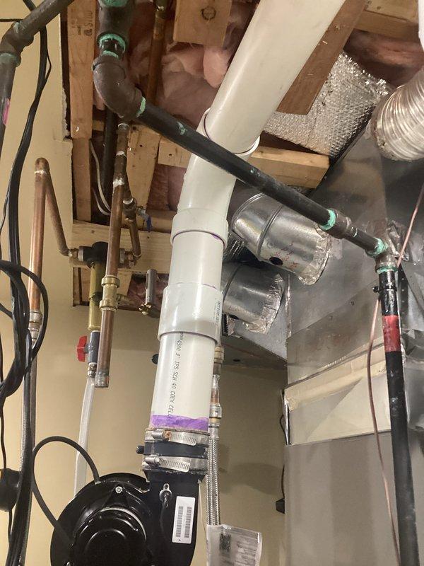 Conducted on-site evaluation for tankless water heater conversion at residential property. Customer currently operates a Lochinvar brand tank-style water heater with integrated recirculation pump system. Assessed existing installation including all supply and return plumbing connections, venting configuration, gas line sizing, and electrical requirements. Documented current equipment specifications and utility room layout. Photographed existing tank water heater installation showing recirculation pump assembly, copper supply lines with shutoff valves, PVC venting system, and associated plumbing infrastructure. Evaluated overhead mechanical space including existing gas lines, water distribution piping, HVAC ductwork proximity, and available clearances for tankless unit installation. Reviewed structural considerations and determined optimal mounting location for proposed tankless system. Assessed required modifications including gas line capacity verification, condensate drain routing, v