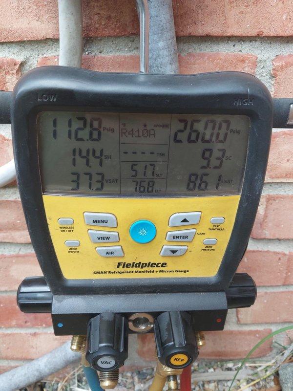 Performed routine maintenance on residential air conditioning system. Connected refrigerant manifold gauges to service ports and recorded operating pressures and temperatures, with readings showing 112.8 PSIG on low side and 260.0 PSIG on high side at 144°F. Inspected outdoor condensing unit exterior condition, verified protective grille integrity, and confirmed proper system operation upon completion of maintenance procedures.