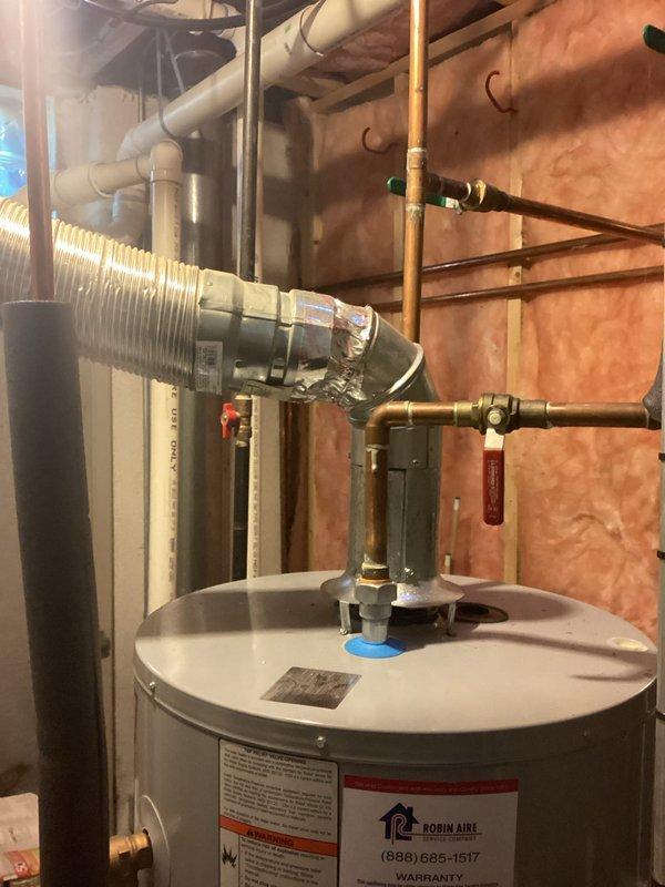 Completed water heater estimate for residential installation in basement mechanical room. Assessed existing water heater unit with copper piping connections, shut-off valves, and proper venting configuration. Documented current equipment specifications, plumbing connections, and installation conditions including exposed wall framing with fiberglass insulation. Photographed water heater unit showing manufacturer labeling, piping layout with brass fittings, red-handled valves, and proximity to existing HVAC equipment. Evaluated mechanical room accessibility and clearances for potential replacement installation.