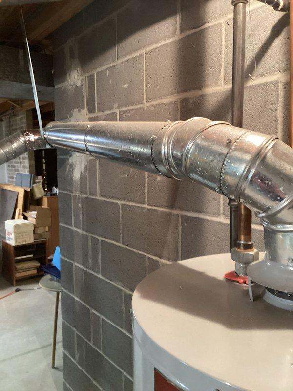 Conducted comprehensive on-site assessment of existing residential water heater installation in basement utility area. Evaluated current unit condition, venting configuration with galvanized metal ductwork, copper supply line connections, and overall system layout. Documented equipment specifications, clearance requirements, and existing plumbing connections to prepare detailed replacement estimate for homeowner consideration.