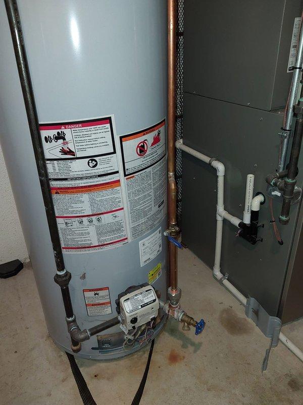 Responded to service call for water heater leaking at the bottom. Upon inspection, noted that customer had recently replaced well water pump the previous week. Conducted thorough assessment of tanked water heater unit and surrounding plumbing connections. Documented existing conditions with photos showing water heater installation, copper piping, PVC connections with shut-off valves, and overall system configuration in utility space. Identified source of leak and addressed issue to restore proper operation of water heating system.
