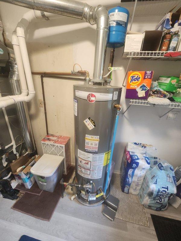 Responded to service call for reported water heater leak. Upon arrival, performed thorough inspection of Rheem Professional series tanked water heater unit and surrounding plumbing connections. Examined all visible components including copper supply lines, brass fittings, temperature and pressure relief valve, drain valve, and tank exterior for signs of moisture or active leaking. Inspected overhead ductwork connections and exhaust vent pipe for proper installation and clearances. Documented equipment condition with photographs showing water heater installation, blue water treatment filter system, and associated mechanical room plumbing infrastructure. Verified warranty status and provided assessment findings for next steps.