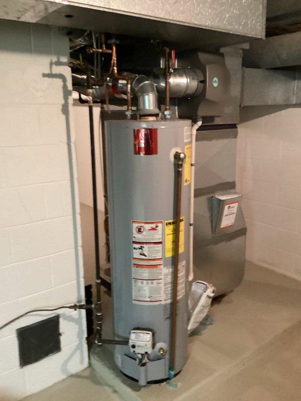 Completed comprehensive water heater estimate for existing residential hot water system. Assessed current installation featuring cylindrical water heater unit with associated copper supply and discharge piping, expansion tank, and connection infrastructure. Documented existing plumbing configuration including vertical and horizontal copper pipe runs with soldered joints, isolation valves, and mounting platform. Photographed complete system layout, mechanical connections, HVAC integration, and basement utility area conditions to provide detailed scope for water heater replacement proposal.