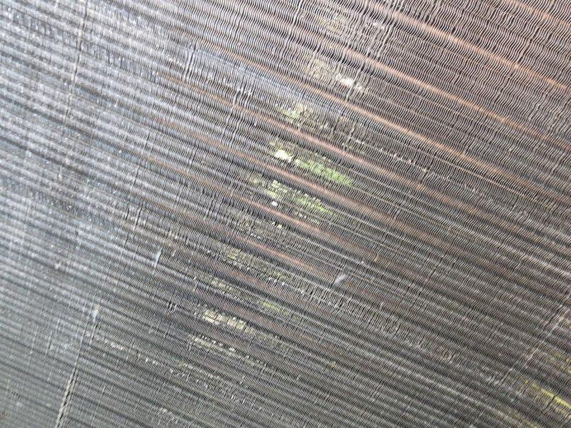 Completed scheduled AC maintenance on condensing unit. Inspected condenser fan motor assembly, compressor components, electrical connections, and capacitor. Noted biological growth and moisture accumulation in base pan requiring attention. Examined condenser coil fins showing dust and debris accumulation on mesh surface. All mechanical and electrical components operational at time of inspection.