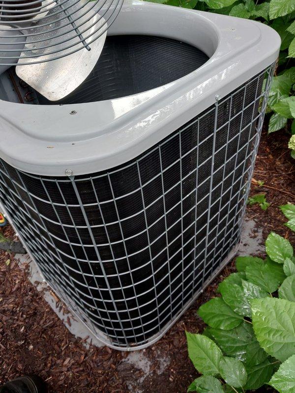 Completed comprehensive preventive maintenance inspection on residential outdoor condensing unit as part of cooling season service agreement. Unit found in good operational condition with protective wire cage intact, condenser coils clean and unobstructed, and proper airflow maintained through heat exchanger fins. Documented equipment condition with photographic records showing well-maintained installation on concrete pad with adequate clearance from surrounding landscaping.