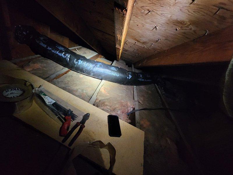 Completed electrical installation work in attic space requiring access through confined crawl area with existing HVAC ductwork and insulation. Navigated around black flexible duct system and fiberglass batt insulation to install or service electrical fixtures and outlets, ensuring all connections met code requirements in the limited-access environment.
