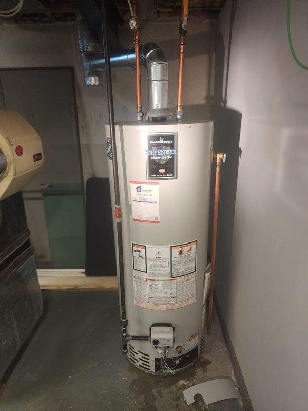 Responded to service call for hot water heater leak and loss of hot water. Upon arrival, inspected Bradford White Defender tank-style water heater in basement utility area. Identified active leak at tank requiring immediate attention. Assessed water heater condition, plumbing connections, and copper piping configuration. Due to compromised tank integrity causing the leak and hot water failure, recommended and completed water heater replacement. Installed new unit with proper copper pipe connections, pressure relief valve, and all required safety components. Tested all connections for leaks, verified proper operation of hot water system, and confirmed restoration of hot water service throughout residence.