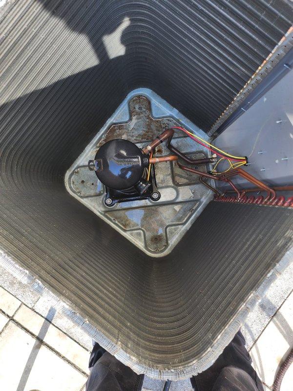 # HVAC Maintenance - Worry Free Service Agreement - Cooling

Performed comprehensive preventive maintenance on rooftop air conditioning condenser unit per Worry Free Service Agreement protocol. Conducted thorough visual inspection of outdoor condenser unit, noting significant rust accumulation and deterioration along bottom frame and base mounting pad requiring monitoring for future replacement consideration. Assessed heat exchanger coil condition, observing heavy dust and debris accumulation on aluminum fins throughout the unit, along with organic matter and dried leaves collected around base perimeter.

Inspected compressor motor and mounting hardware, documenting advanced corrosion on galvanized mounting plate and surrounding components. Verified electrical connections and wiring integrity, with red, yellow, and black conductor wires and copper refrigerant lines examined for secure connections and proper routing. Evaluated overall unit weathering and exterior surface deterioration c
