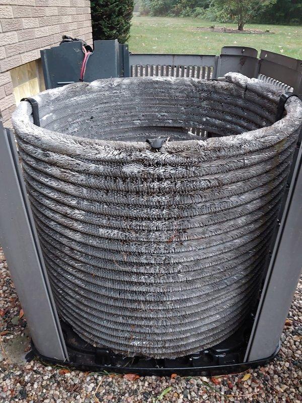 Completed preventive maintenance on outdoor condensing unit with cylindrical coil configuration. Unit exhibited severe debris accumulation on heat exchanger coil fins, with thick layers of dust, lint, and airborne particles substantially restricting airflow and reducing system efficiency. Thoroughly cleaned condenser coils to restore proper heat transfer capabilities and airflow. Inspected compressor, electrical connections, and all accessible components during maintenance service. Unit restored to optimal operating condition per Worry Free Service Agreement specifications.