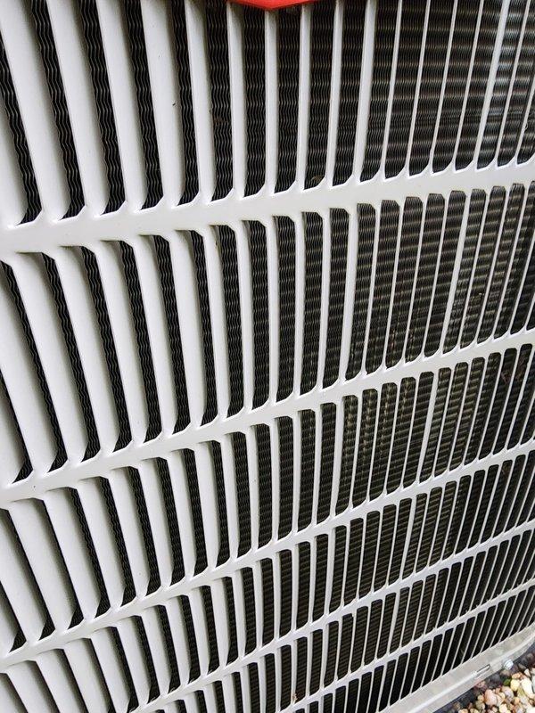 Performed comprehensive AC tune-up on 5-year-old outdoor condenser unit located at northwest corner of property. Conducted full system inspection including condenser coil examination, fan motor operation check, refrigerant line assessment, and electrical connection verification. Unit showed normal wear consistent with age, with minor debris accumulation and surface oxidation noted on internal components. Cleaned condenser coils, verified proper airflow through heat exchanger fins, and inspected compressor housing and mounting. All electrical wiring connections secure with no signs of degradation. Refrigerant lines intact with no visible leaks or damage. Fan motor operating smoothly with protective grille properly secured. System operational and performing within manufacturer specifications upon completion of maintenance service.