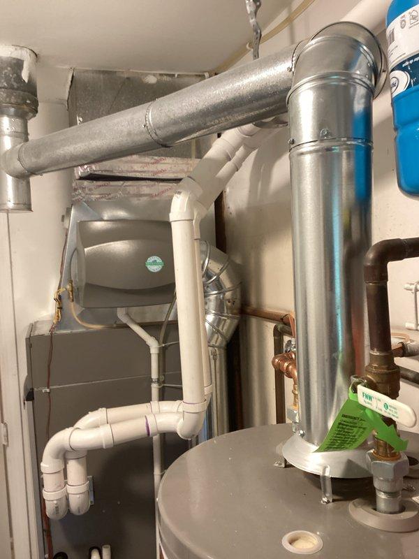 Completed estimate for water heater replacement in residential utility space. Evaluated existing water heater system with gray storage tank, blue pressure tank, copper supply lines, and metal venting configuration. Assessed current plumbing connections including brass fittings and shutoff valves. Documented equipment specifications and mechanical room layout to provide replacement options and pricing for new water heater installation.