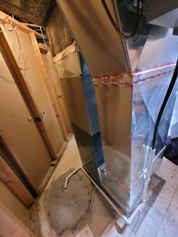 Completed installation of Bryant air conditioning system in residential basement utility room. New air handler unit was positioned and secured, with all necessary refrigerant lines, electrical connections, PVC condensate drainage, and supply ductwork properly installed and sealed to manufacturer specifications. Retrieved customer's portable air conditioning unit from premises as requested.