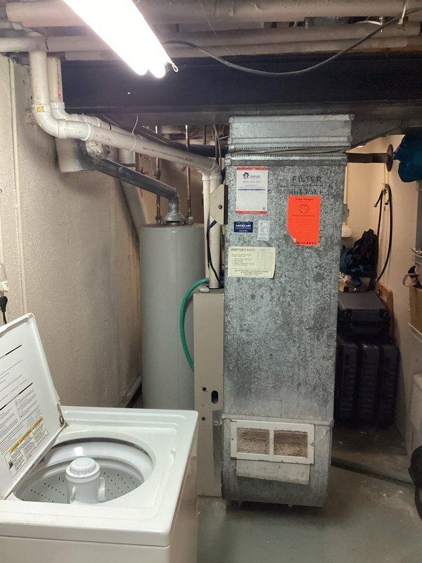 Conducted HVAC system evaluation for replacement estimate on aging equipment including an R22 air conditioning unit from 2014 experiencing low refrigerant levels and a furnace dating from 2002. Documented existing basement mechanical room configuration with photographs showing current equipment layout, including the aged furnace unit with visible wear on galvanized exterior, associated ductwork, and plumbing infrastructure. Assessed system compatibility and prepared comprehensive replacement recommendations for complete HVAC system upgrade.