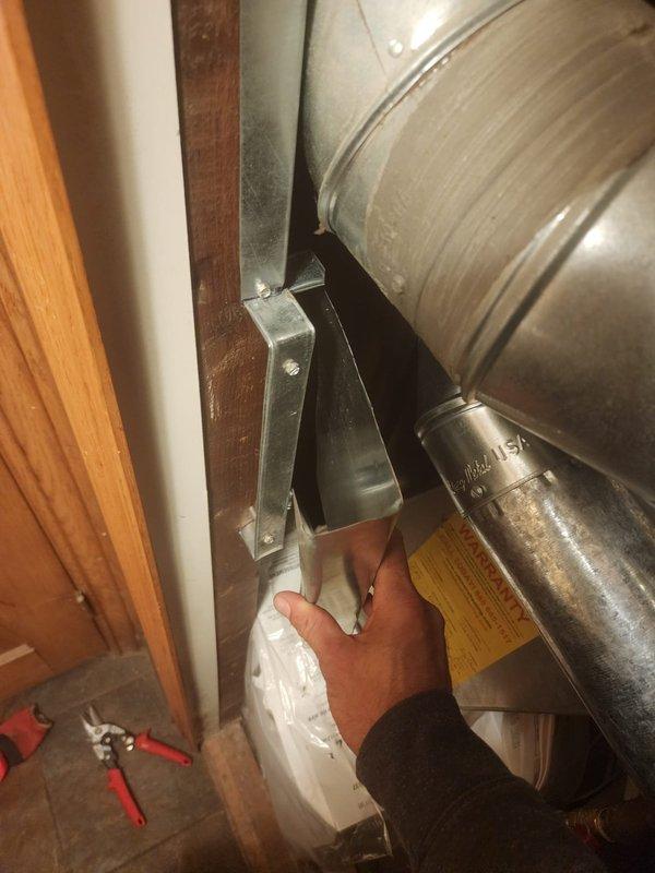 Responded to warranty inspection regarding furnace exhaust vent clearance violation at closet corner installation. Upon arrival, identified that the exhaust ductwork was installed too close to combustible door frame materials, with the clearance reduction method not meeting requirements specified in Section #308 of the 2021 Michigan Mechanical Code, which mandates a minimum 1" air space between metal ductwork and combustible materials, including proper spacing for metal stand-offs and mounting screws. Documented the code violation with photographs showing the improper mounting bracket installation on the wooden framing member and the insufficient clearance between the galvanized steel ductwork and adjacent door trim. Advised that corrective action is required to bring the installation into compliance with current mechanical code standards.