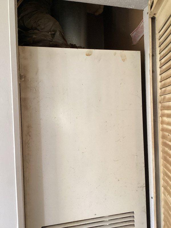 Completed comprehensive assessment of existing HVAC system located in interior utility closet for equipment replacement estimate. Documented current unit condition, noting aged furnace cabinet with significant dust accumulation, discoloration, and wear patterns consistent with extended service life. Photographed accessible components including ventilation grilles, access panels, and surrounding installation space to evaluate replacement requirements and clearance specifications for new equipment installation.