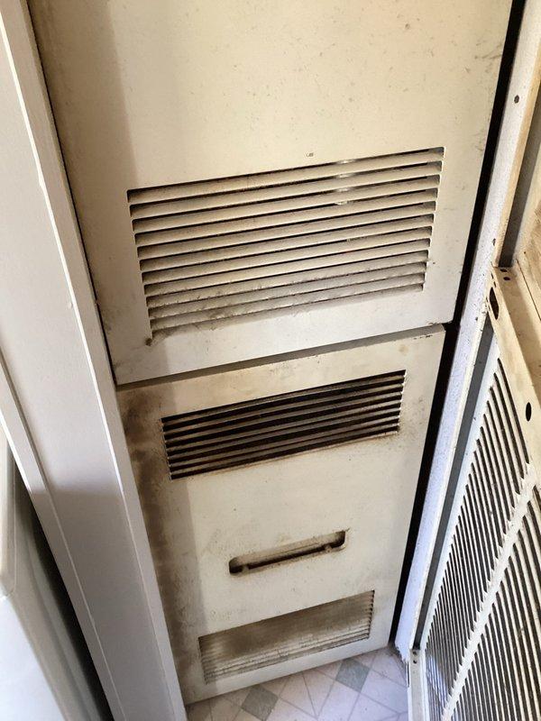 Completed comprehensive assessment of existing HVAC system located in interior utility closet for equipment replacement estimate. Documented current unit condition, noting aged furnace cabinet with significant dust accumulation, discoloration, and wear patterns consistent with extended service life. Photographed accessible components including ventilation grilles, access panels, and surrounding installation space to evaluate replacement requirements and clearance specifications for new equipment installation.