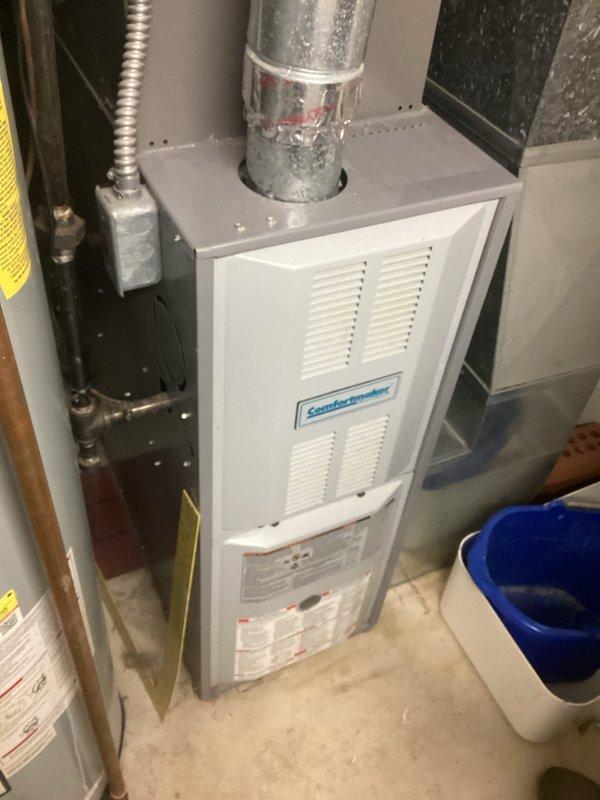 Provided estimate for replacement of 20+ year old Comfortmaker furnace system currently located in basement mechanical room. Existing natural gas furnace remains operational but has reached end of expected service life, with visible condensation on ductwork and aging components requiring replacement to ensure continued reliable heating performance.