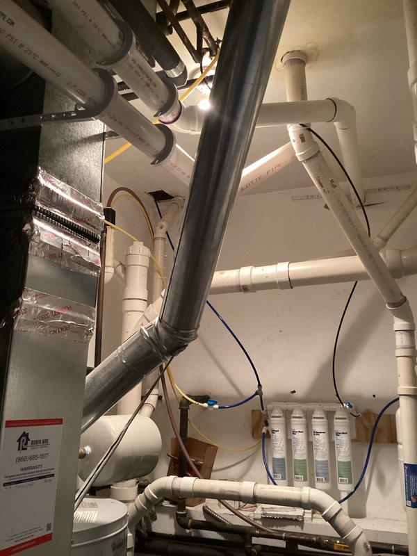 Conducted comprehensive water heater replacement estimate at 3:30 PM in mechanical utility room. Assessed existing water heater installation, evaluated current plumbing configuration including white PVC piping, galvanized steel supply lines, copper connections with brass fittings, and Water Worker blue pressure tank. Documented existing water filtration system with four-stage filter housings, photographed HVAC ductwork with reflective insulation, and noted all electrical connections and mounting requirements for accurate replacement specifications.