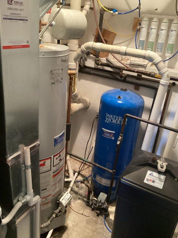 Conducted comprehensive water heater replacement estimate at 3:30 PM in mechanical utility room. Assessed existing water heater installation, evaluated current plumbing configuration including white PVC piping, galvanized steel supply lines, copper connections with brass fittings, and Water Worker blue pressure tank. Documented existing water filtration system with four-stage filter housings, photographed HVAC ductwork with reflective insulation, and noted all electrical connections and mounting requirements for accurate replacement specifications.