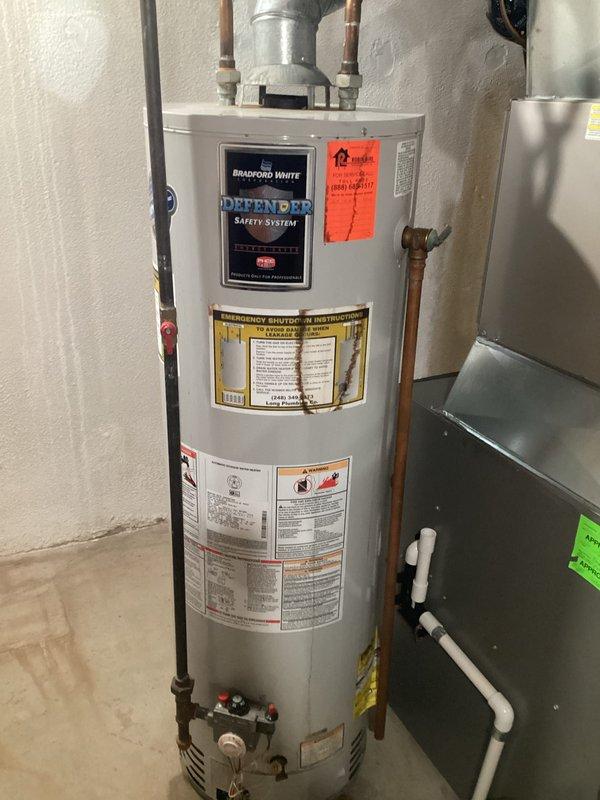 Responded to service call for leaking water heater. Upon inspection, found 25-year-old Bradford White Defender Safety System water heater showing signs of failure with active leak. Unit had exceeded its expected service life and was determined to be beyond economical repair. Documented existing installation including copper supply lines, gas control valve configuration, overhead plumbing connections, and proximity to HVAC equipment. Provided comprehensive estimate for complete water heater replacement, including removal of existing unit, installation of new water heater with proper venting, gas line connections, and code-compliant copper piping. Photographed current installation conditions and equipment specifications for replacement planning purposes.