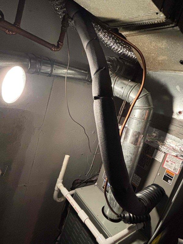 Completed warranty recall service addressing multiple installation deficiencies on HVAC system. Installed cover on A2L refrigerant junction box per safety requirements, corrected condensate drain connection at evaporator coil to ensure proper drainage, repaired torn insulation on interior refrigerant line set to maintain system efficiency, and re-secured MC cable with proper strapping for code compliance. All corrections verified and documented with photographic evidence showing equipment installation, ductwork connections, and utility room configuration.