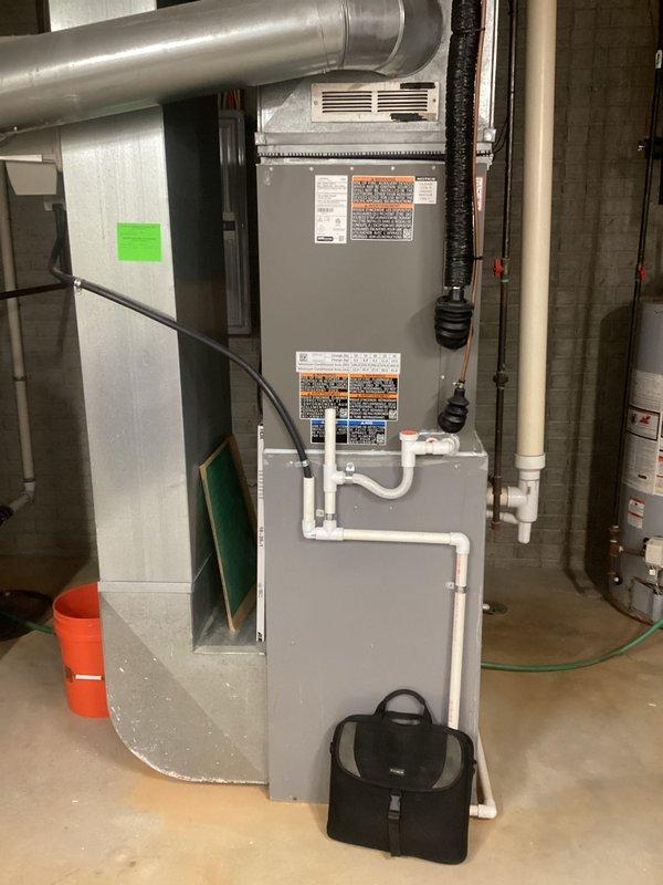 Conducted comprehensive assessment of existing HVAC furnace and hot water heater for replacement estimate in residential basement mechanical room. Evaluated gray metal vertical cabinet-style furnace unit with existing PVC venting system and metallic ductwork configuration. Documented water heater showing significant rust corrosion on top surface, indicating end-of-service-life condition requiring replacement. Photographed all equipment specifications, current piping configurations including copper and PVC connections, and existing venting arrangements to provide accurate equipment sizing and installation planning for proposed system replacements.