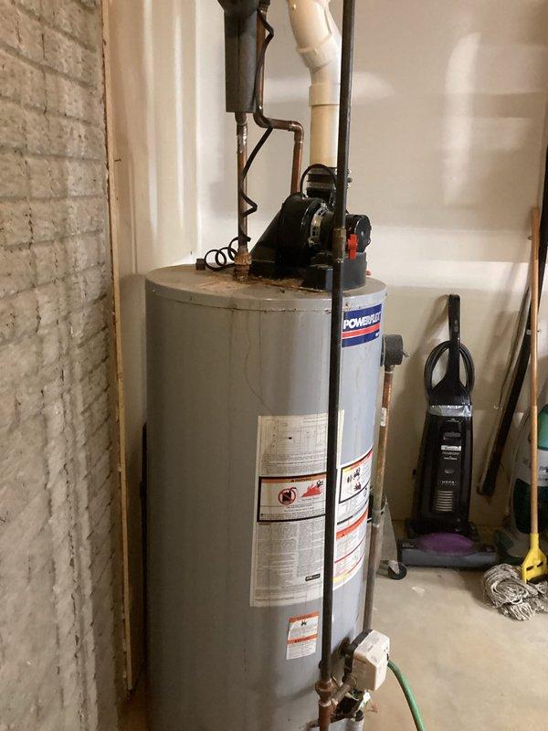 Conducted comprehensive assessment of existing HVAC furnace and hot water heater for replacement estimate in residential basement mechanical room. Evaluated gray metal vertical cabinet-style furnace unit with existing PVC venting system and metallic ductwork configuration. Documented water heater showing significant rust corrosion on top surface, indicating end-of-service-life condition requiring replacement. Photographed all equipment specifications, current piping configurations including copper and PVC connections, and existing venting arrangements to provide accurate equipment sizing and installation planning for proposed system replacements.