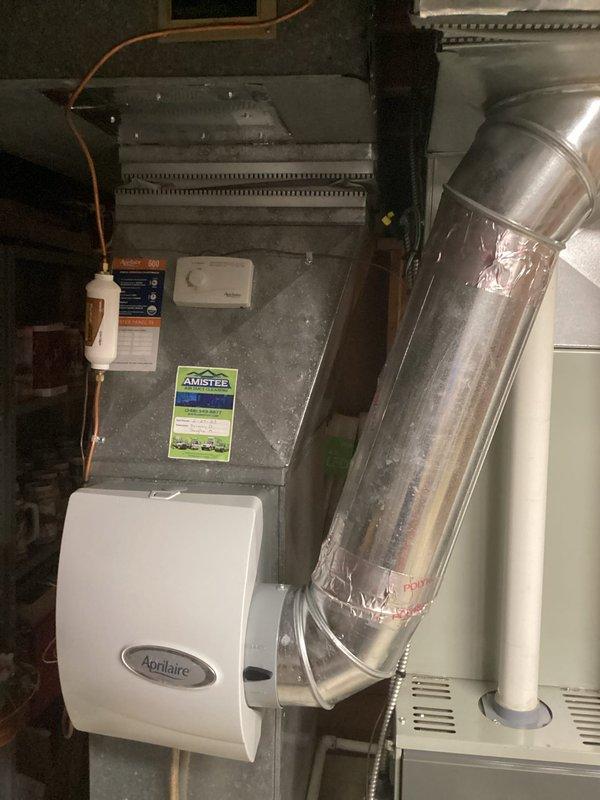 Conducted on-site evaluation of existing HVAC system for replacement estimate following previous contractor's recommendation that furnace required replacement. Assessed current equipment including gray metal air handler/furnace unit with Aprilaire humidifier attachment, evaluated refrigerant line connections, condensate drainage system with white PVC piping, and ductwork configuration in basement utility area. Documented existing system specifications and installation conditions to provide comprehensive replacement options.