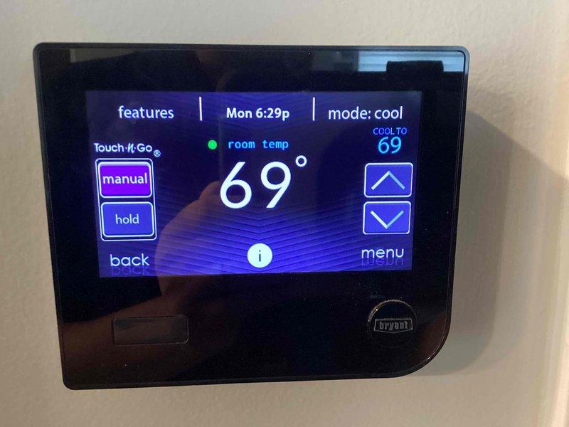 Completed installation of Bryant air conditioning system including new outdoor condensing unit and indoor air handler. Installed and programmed Bryant digital thermostat with touchscreen interface, verified proper operation in cooling mode with temperature reading at 69 degrees. System tested and confirmed operational, financing paperwork completed and identification documentation collected.