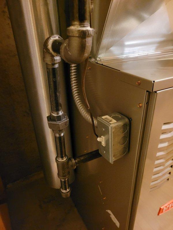 Successfully installed a new Bryant 80% efficiency furnace in the mechanical space. The installation included proper gas line connections with flexible corrugated connectors and threaded fittings, aluminum flex ductwork routing from the unit with secure black strap mounting, and appropriate electrical controls with wall-mounted disconnect switch. Unit was positioned against concrete foundation walls on finished flooring, with all connections properly secured and tested for safe operation.