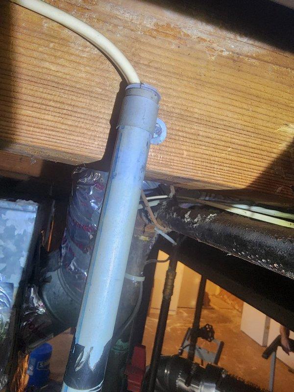 Completed warranty service by installing inspector-recommended Arlington bushing (SKU#4001) on PVC pipe penetration through wooden structural surface. Secured piping with appropriate support bracket and fasteners, ensuring proper protection of pipe where it passes through building materials per code requirements. Documentation photos captured showing installed bushing and completed work in attic space.