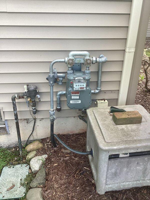 Conducted site assessment for upcoming generator installation scheduled for 9/29. Documented existing electrical infrastructure including main meter assembly, weathered junction box, and conduit routing on exterior wall. Photographed gas meter location and utility connections to verify clearances and placement requirements for generator unit in rear yard. Confirmed site plan requirements and noted installation parameters specifying 2-4 schedule with rigid conduit specifications prior to 2-pole connection point.