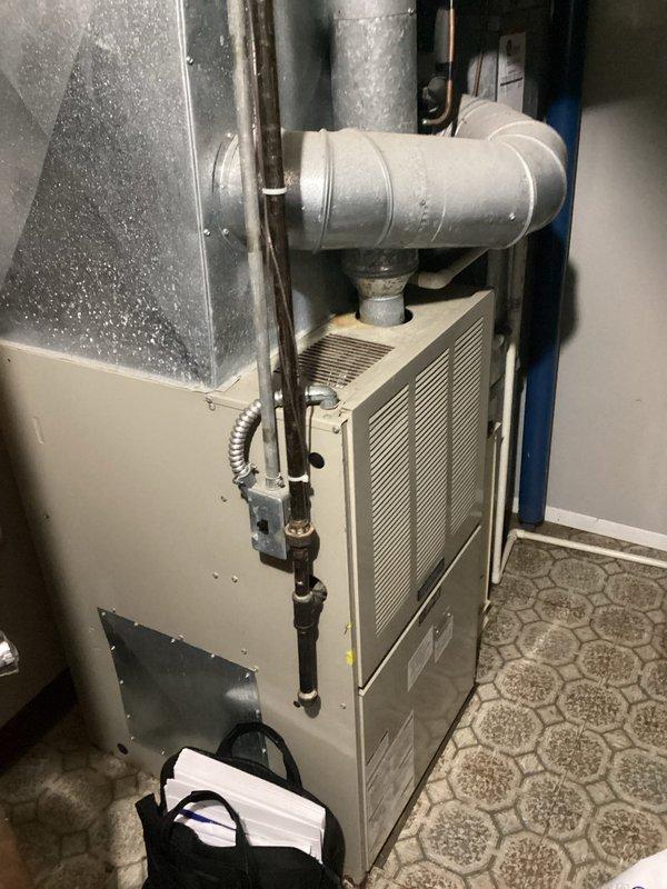 Conducted comprehensive water heater evaluation and assessment of existing HVAC system in residential utility space. Inspected white cylindrical tank-style water heater unit, documenting current installation configuration, plumbing connections, and valve controls. Evaluated beige furnace unit with adjacent ductwork and examined condensate drainage system with white PVC piping. Photographed all mechanical equipment, pipe routing, and system components to support estimate preparation for potential water heater replacement and full system upgrade considerations.