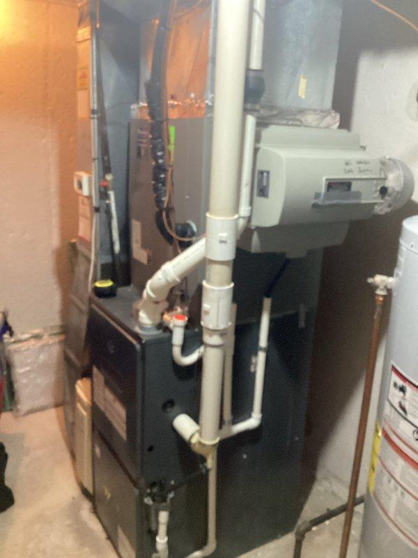 Completed furnace replacement estimate for residential basement installation. Evaluated existing dark-colored furnace unit with white PVC venting system, water heater, and electrical panel configuration in mechanical room. Documented current HVAC system layout including ductwork, piping arrangements, and thermostat controls for unit 404 to provide comprehensive replacement quote.