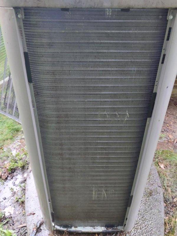 Completed comprehensive cooling season maintenance inspection on residential air conditioning system. Outdoor condenser unit examined and photographed, showing significant accumulation of dirt and debris on heat exchanger fins requiring attention during routine service interval. Indoor refrigerant lines and system components inspected and documented, with copper tubing and connections found in serviceable condition with normal aging characteristics present.